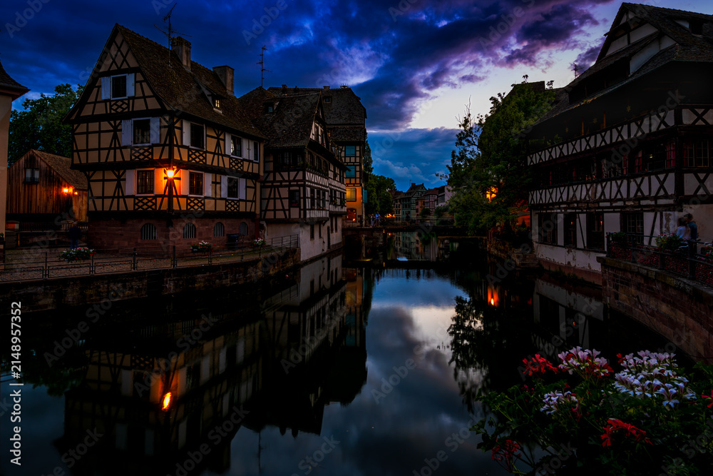 Obraz premium Half-timbered houses beside a canal with reflections under a dramatic blue hour sky