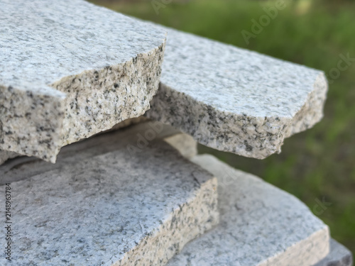 Obraz na płótnie Gray granite paving slabs stacked outdoors with green grass background