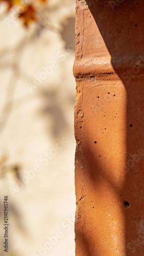 Red terracotta clay pot rim with curved texture pattern under warm sunlight