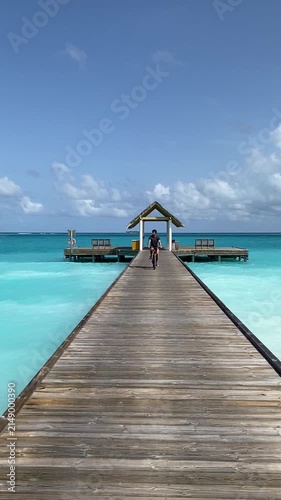 Cycling through the Maldives, endless turquoise ocean, tropical island, wooden path, bright sunny day, crystal-clear water, cinematic, ultra-realistic