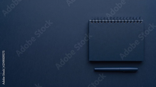Minimalist Dark Blue Notebook and Pen on a Solid Background.