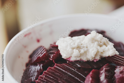 Fresh sliced beetroot salad topped with spicy grated horseradish in a white bowl