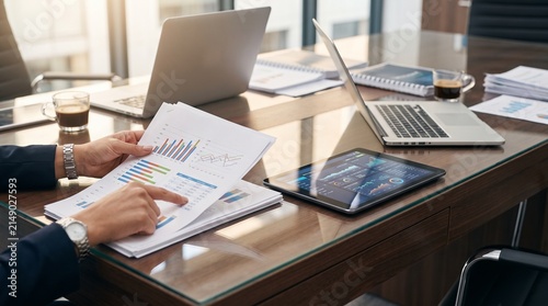 Hands Comparing Printed Reports with Digital Dashboard