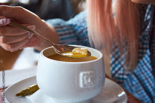 Woman tasting traditional romanian tripe soup with garlic and sour cream from white bowl