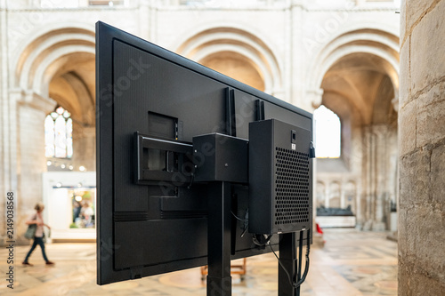 Shallow focus of the rear of a large plasma TV located in a famous English cathedral. The screen displays the main service to the congregation who may be too far away to see the service properly.
