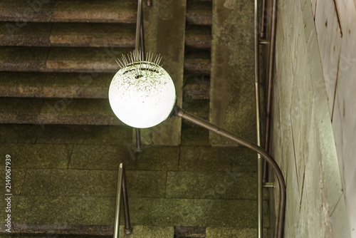 Konstfotografi Spherical outdoor lantern with metal bird deterrent spikes glowing beside dark s