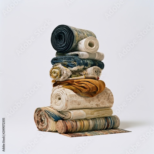 Carpets lie coiled against white backgrounds as home decor.