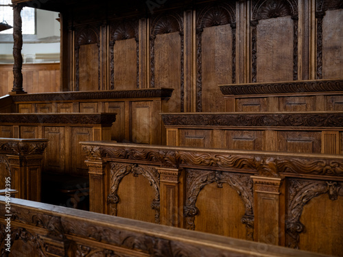 Rows of carved oak choir stalls with scallop shell arched panels and foliate friezes in a historic church, heritage seating and woodwork.