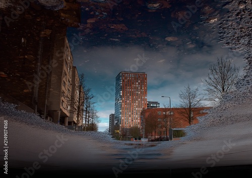 Urban Reflection - Cityscape Mirrored in a Puddle at Dusk.