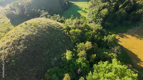 FPV aerial view of the iconic Chocolate Hills landscape featuring lush green conical mounds and tropical vegetation in Batuan, Central Visayas, Philippines.