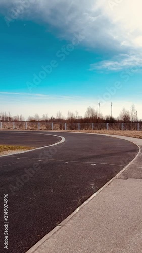 Close-up running track asphalt surface curve showing granular rubber texture, faded lane marking and grassy verge, empty prerace