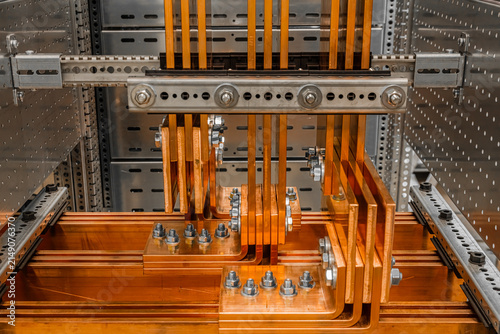 View of copper busbars and electrical components inside an industrial power distribution panel in Latvia.