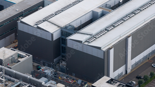 Aerial view of a large modern industrial data center building featuring extensive rooftop cooling systems and metal cladding in Slough, England, United Kingdom.