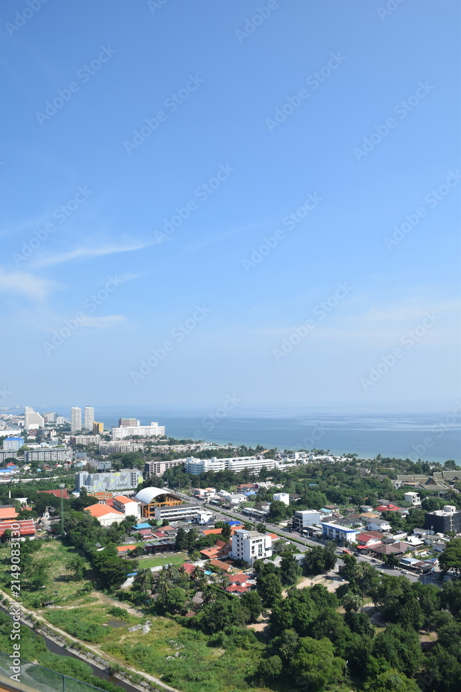 Fototapeta premium High angle vertical aerial view of coastal town, buildings, green trees, and sea view in Thailand
