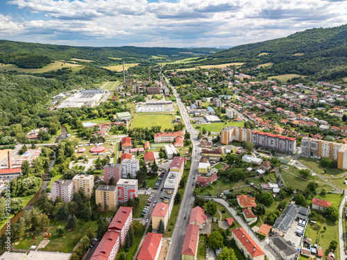 Aerial view of the Housing estate sidlisko 1. maja featuring residential apartment buildings, green spaces, and surrounding hills under a cloudy sky in Hnusta, Banska Bystrica Region, Slovakia.