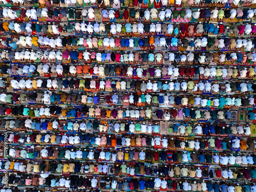 Aerial view of a large congregation of people praying in organized rows on colorful prayer mats during a religious gathering in Kushtia, Khulna Division, Bangladesh.
