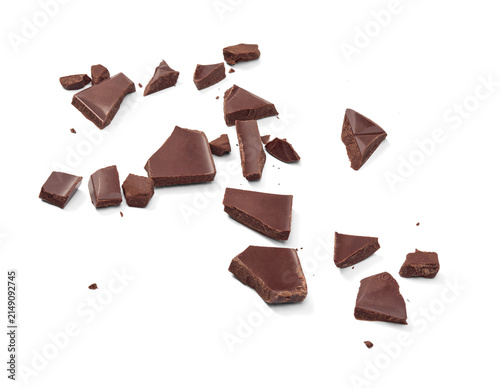 Several irregular pieces of dark chocolate are scattered across a white background. Chocolate pieces isolated. The pieces vary in size and shape, displaying a rich brown color and a matte texture.