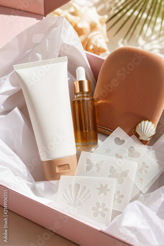 Self tanning gift box with skincare products and stencils. Sunless tanner kit with mitt, dropper bottle, and sun tan tattoo templates. Beauty subscription box concept