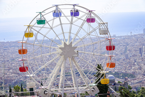 View of the colorful Ferris wheel at Tibidabo Amusement Park overlooking the sprawling cityscape of Barcelona, Catalonia, Spain.