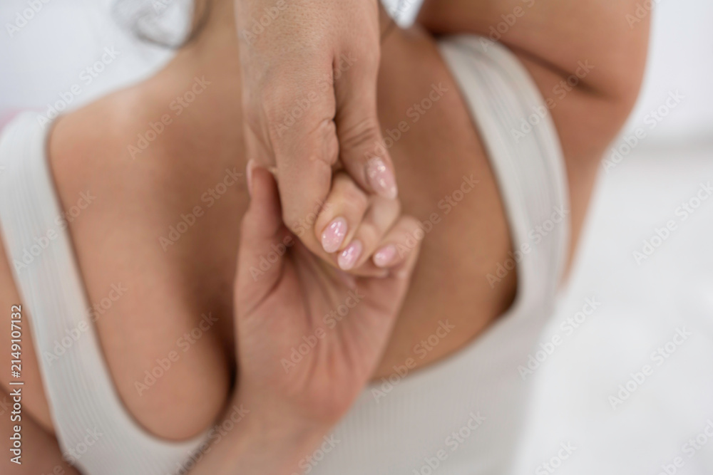 Fototapeta premium Upper body stretch performed by young woman wearing white activewear top holding hands behind back
