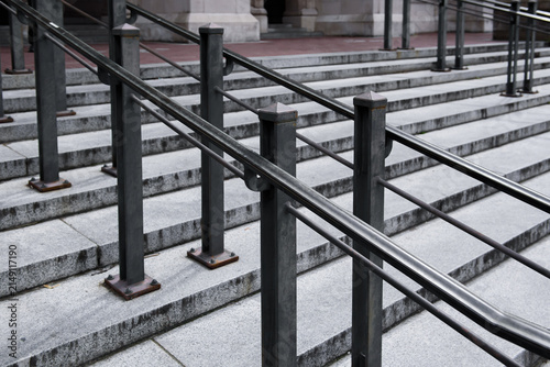 Black metal handrail with sturdy posts mounted along stone steps, featuring a clean and functional design commonly found in commercial and public architecture.