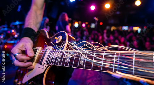 Electric Guitar Strings Vibrating During Live Performance on Stage with Crowd and Lights