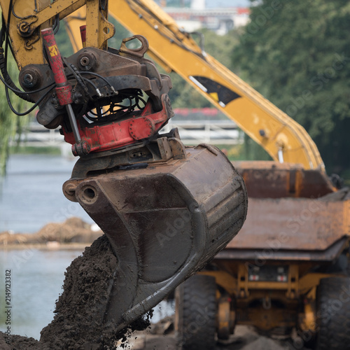 EXCAVATOR AND ARTICULATED HAULER - Construction machines are working on the river

