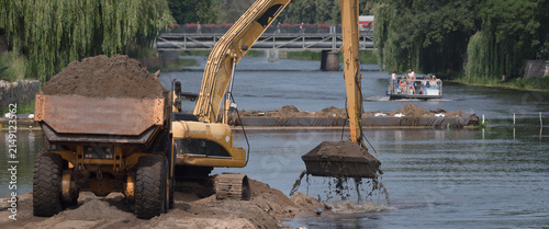 EXCAVATOR AND ARTICULATED HAULER - Construction machines are working on the river
