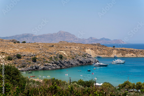 Canvastavla Lindos Beach surrounded by hills and blue water on a sunny day