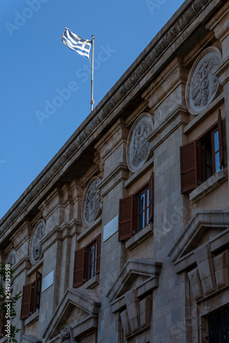 Greek flag flies above a historic building in Rhodes