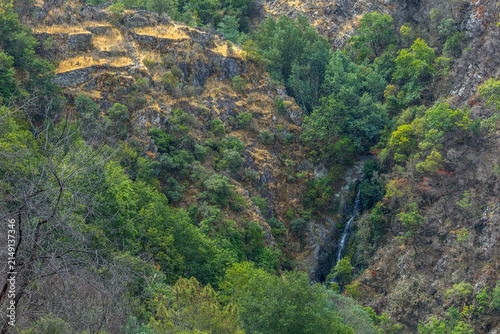 A small hidden waterfall cascades down a rocky mountain