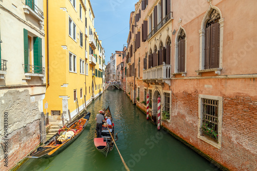 Canvas Print Gondola Carrying Tourists Through a Historic Canal in Venice, Italy