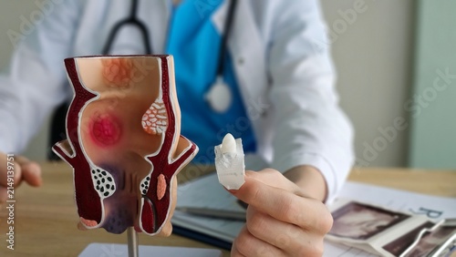 Bild auf Leinwand Proctologist doctor inserting rectal suppository into artificial model of human