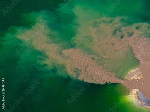 Aerial view of a post-industrial lake in Poland, showing a plume of sediment-rich water mixing with the clear green lake water.