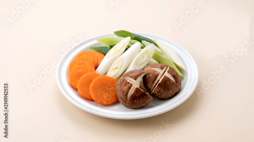 a precise vegetable assortment for nabe hot pot round slices of carrot, diagonal cuts of negi leek, and quartered shiitake mushrooms 