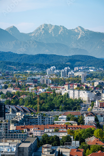 Fotografía Telephoto view of Ljubljana urban skyline with the Kamnik Savinja Alps rising beyond residential districts, business buildings and green neighborhoods in Slovenia