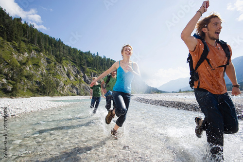 Germany, Bavaria, T�lzer Land, Young friends running through river