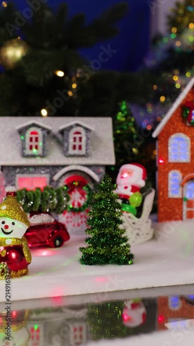 A yellow car with a Christmas tree on its roof drives past the Christmas village