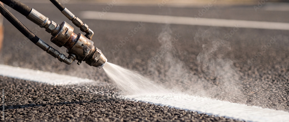 Obraz premium Road line painting with thermal paint sprayer applying white road marking on asphalt