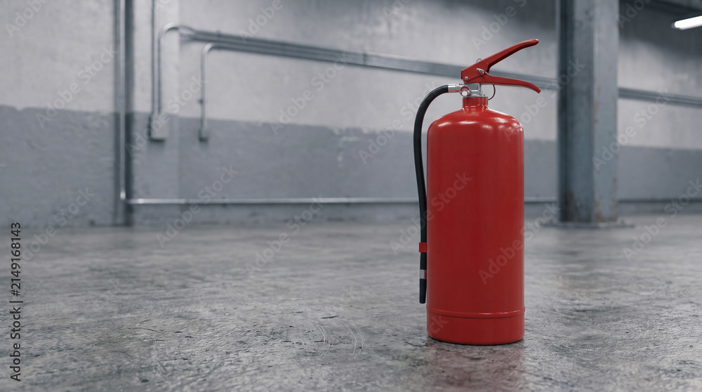 Obraz premium Red fire extinguisher standing on a concrete floor in an empty industrial building providing safety and emergency protection