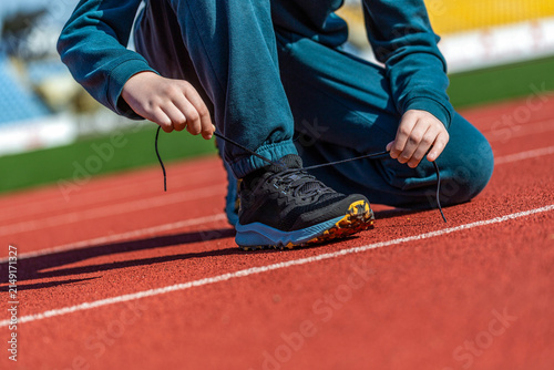 Hands tying shoelace on running shoes before practice. Sport active lifestyle concept. Laces, sneakers, hands. Runner getting ready for training