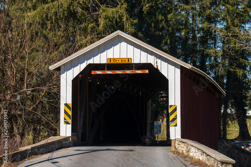 Covered bridge at sunset in rural area with trees around the road