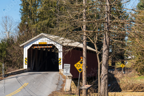 Old covered bridge located on a rural road surrounded by trees in the daytime