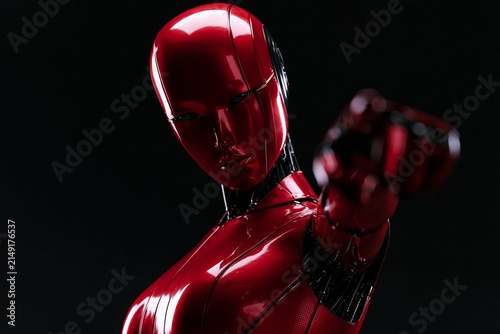 Futuristic red robot with glossy metallic surface pointing forward against a black background in a close-up angled view