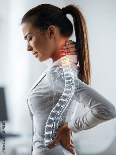 Junge Frau mit Rückenschmerzen hält sich an die Hüfte, während eine medizinische Darstellung der Wirbelsäule eingeblendet ist. Konzept für Orthopädie, Physiotherapie und Rückengesundheit.