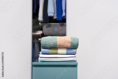 Принти на полотні Folded pastel color striped woolen, warm sweaters with open wardrobe on light gray background
