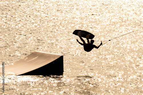 Wassersport - Sportler springt beim Wakeboarden	über Schanze
