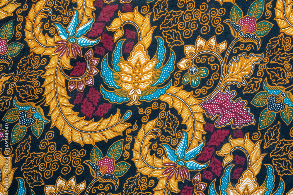 Fototapeta premium Traditional Indonesian batik pattern featuring intricate floral motifs and organic shapes in a vibrant blend of gold, blue, and magenta. 