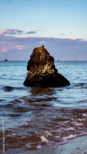 Serene seascape with solitary rocky island under blue sky.