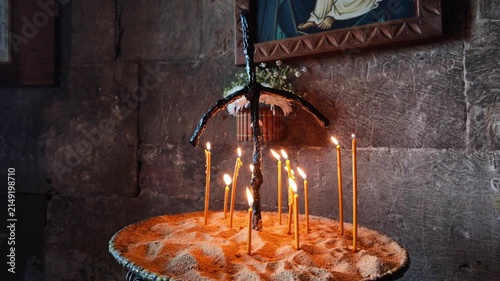 Burning wax candles in a traditional church candlestick standing against a stone wall, symbolizing faith, prayer, hope, spiritual ritual and religious devotion